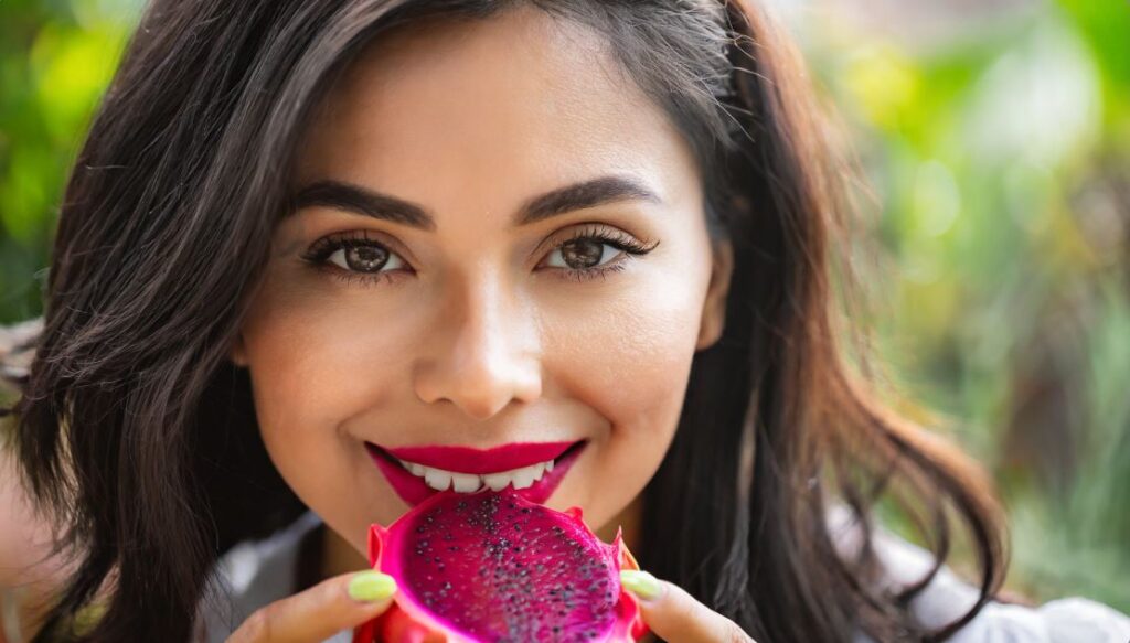 A young woman eating a dragon fruit