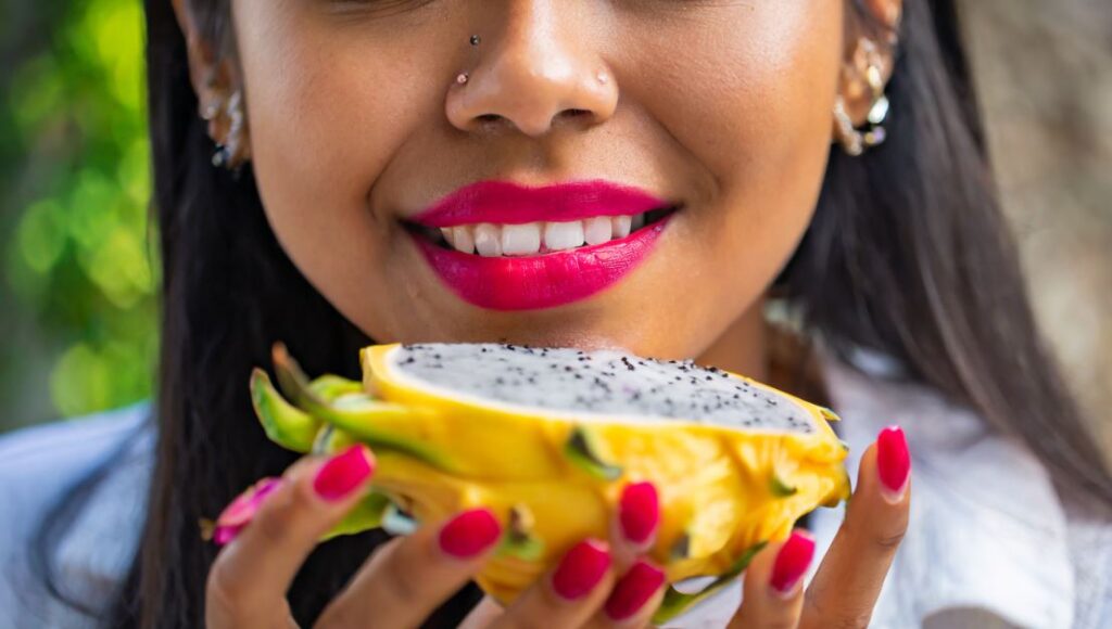 A young woman going to eat a yellow dragon fruit