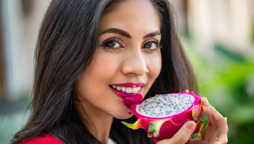 A young women with a red dragon fruit