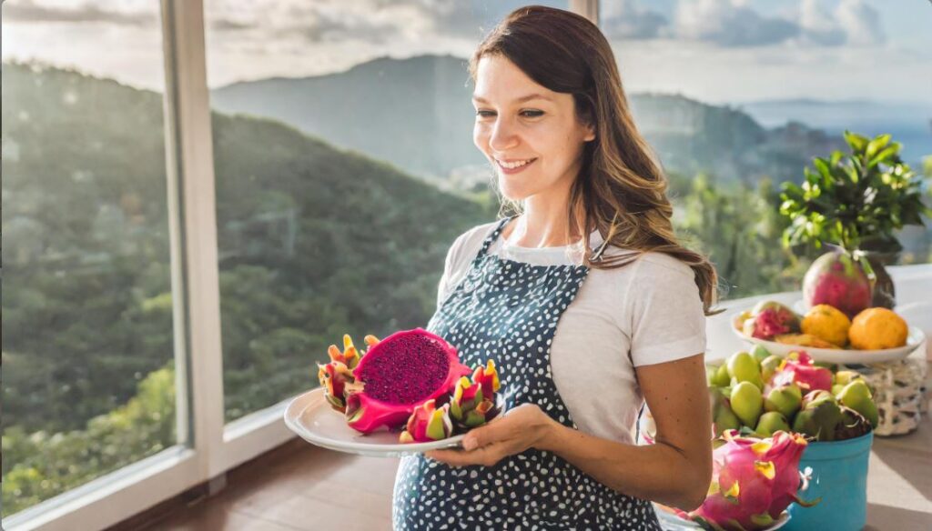 A pregnant woman with a plate full of dragon fruits.